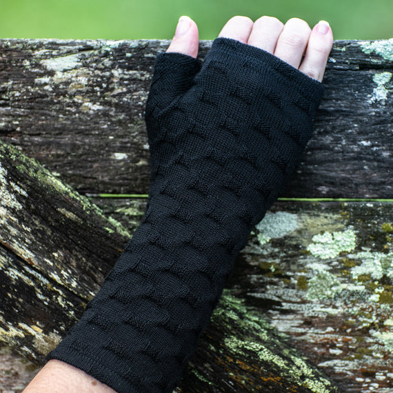 Beautiful Black fingerless glove on a womens hand touching a fence.