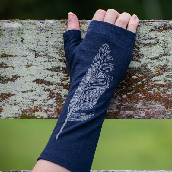 Beautiful Navy with silver feather, fingerless Merino Wool glove on a womens hand touching a fence.