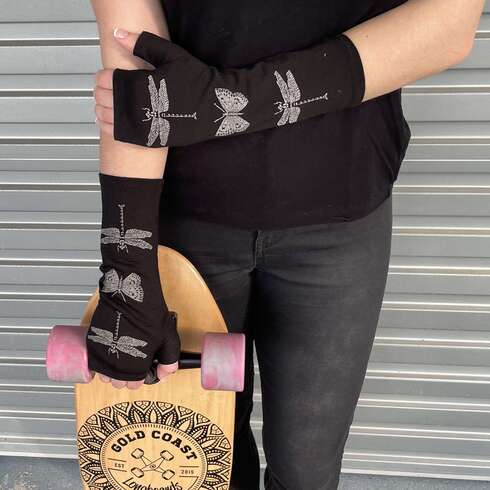 Georgous Black merino wool gloves with butterfly and dragonfly print. On womans hand holding a skateboard.